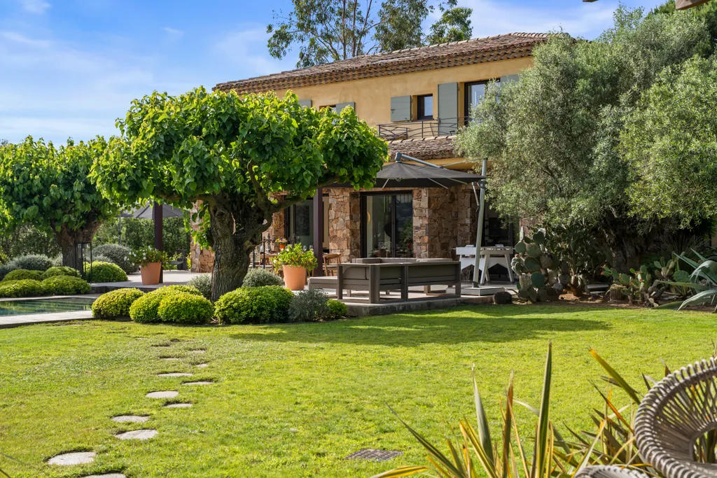 The villa's stone-and-ochre façade from the lawn, a wisteria in bloom by the terrace