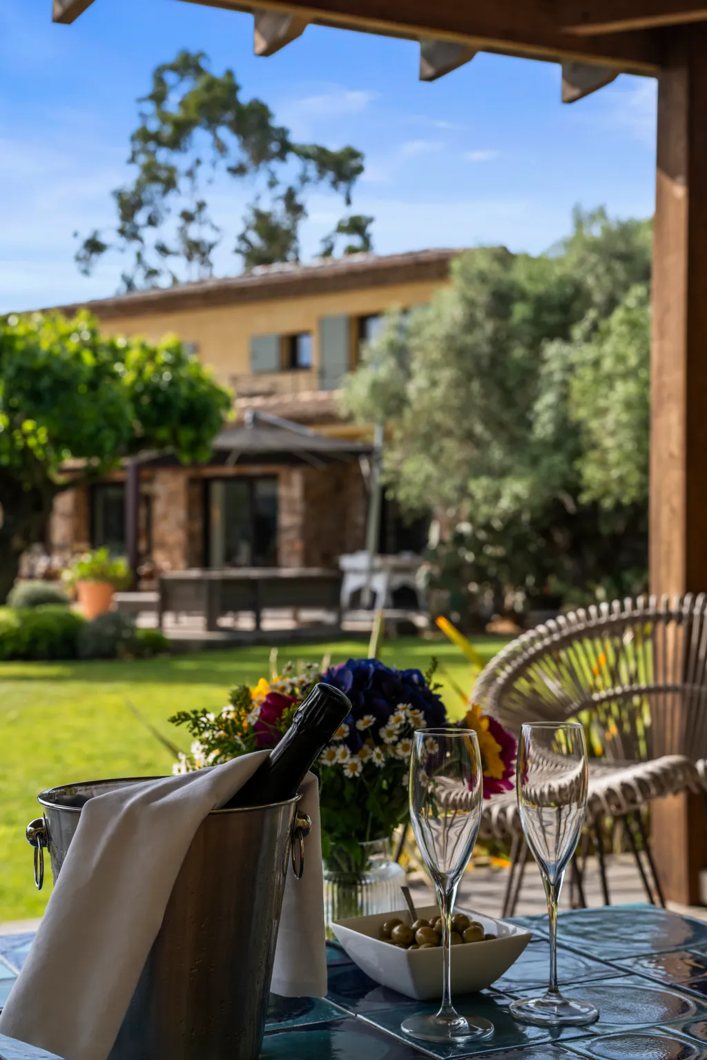Rosé on a terrace table beneath the loggia, the sunlit garden and villa behind