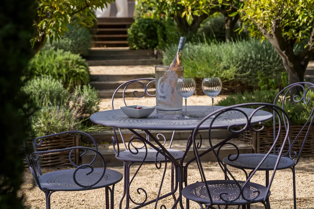 A garden dining table set with rosé, stone steps and lavender rising behind