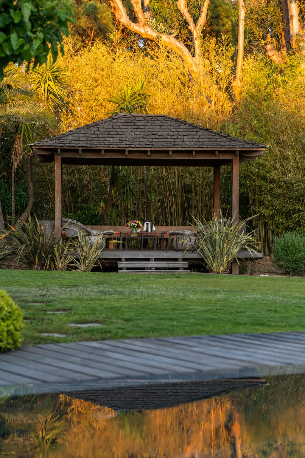 The garden pavilion at golden hour, its bamboo backdrop lit warm by the low sun