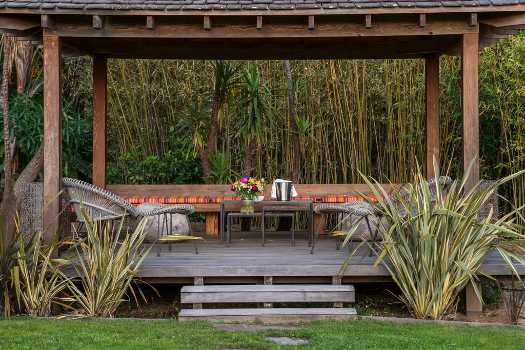 The timber pavilion and its seating at dusk, framed by bamboo and palms