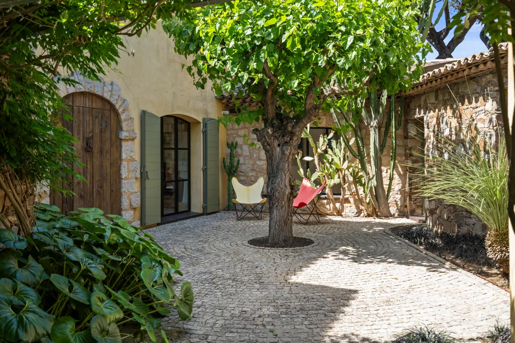 The enclosed courtyard by day — an arched door, butterfly chairs and a shade tree