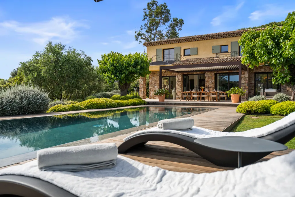 The stone villa and its loggia across the pool, loungers in the foreground