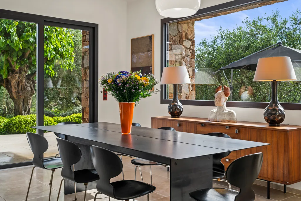 The indoor dining area, a black table beside a walnut credenza and garden windows